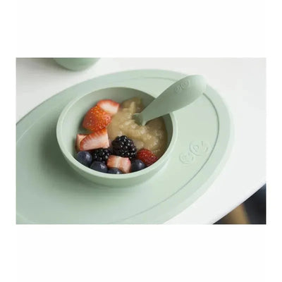 First Foods Set in sage color featuring a bowl with applesauce and mixed berries, including strawberries and blueberries.