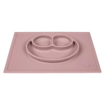 Silicone placemat in blush color featuring a smiley face design with two compartments for food.