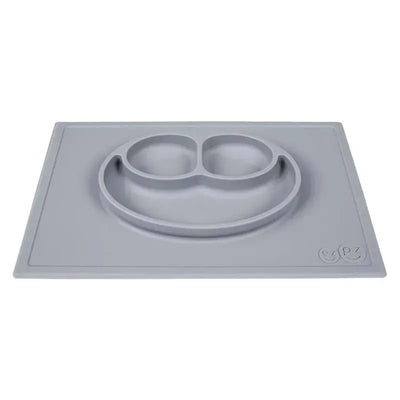 Silicone feeding mat in pewter with a smiley face design and two divided sections for food.
