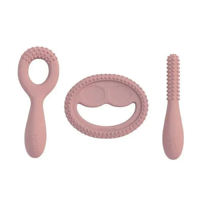 Set of three blush silicone oral development tools for infants, including a teether with a ring, a textured oval, and a slim massager.
