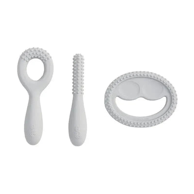Three Ezpz oral development tools in pewter color: textured teether, brush, and spoon designed for infants.