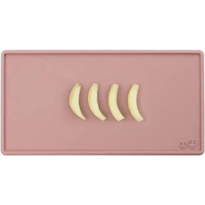 Tiny placemat in blush color featuring four banana slices arranged on it.