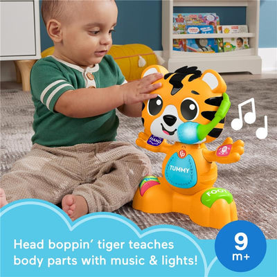 Interactive Fisher Price Bop & Groove Tiger toy with lights and music; a toddler engages by touching its colorful buttons.