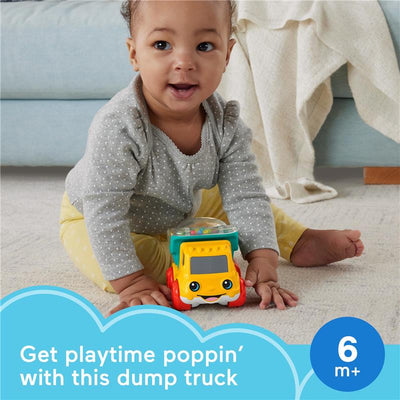 A baby plays with a colorful Fisher Price dump truck toy designed for children 6 months and older, sitting on a soft carpet.