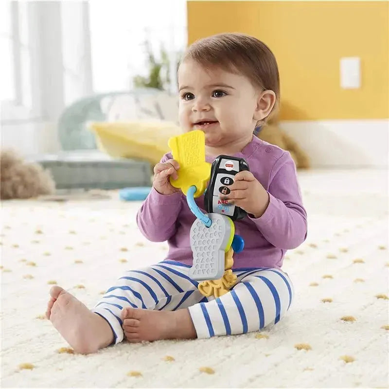 Child sitting on a soft rug, holding Fisher Price Laugh & Learn toy keys with colorful attachments, smiling.