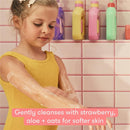Young girl applying Frida for Kids Body Wash on her arms, surrounded by colorful bottles in a bathroom setting.