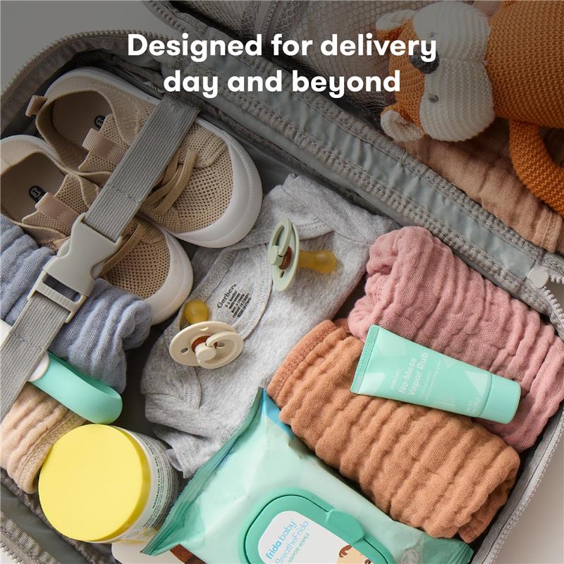 Travel bag containing baby essentials: clothing, pacifiers, wipes, lotion, and a stuffed animal, designed for delivery day.