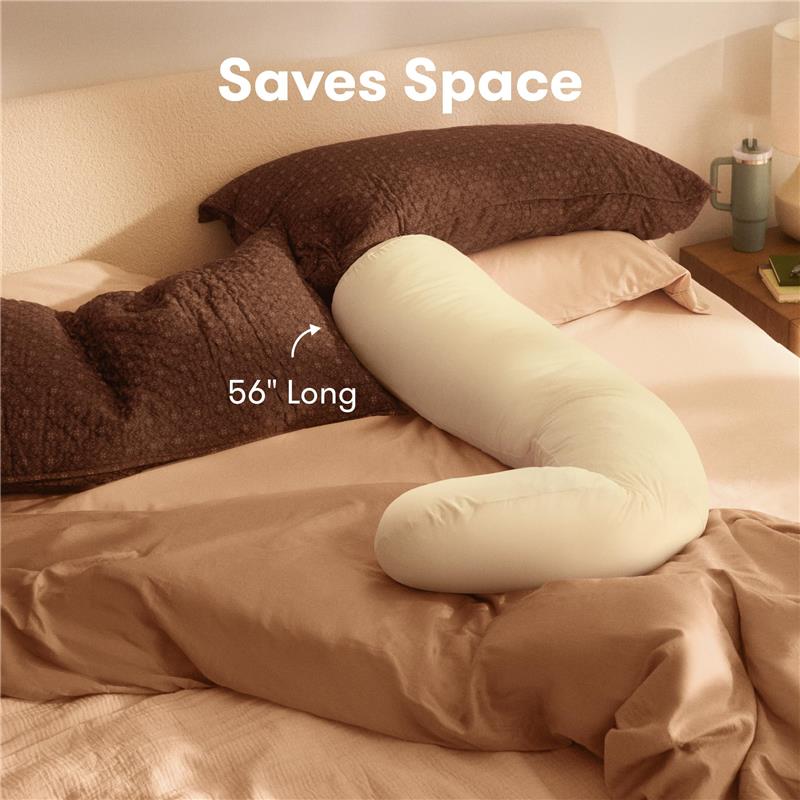 Frida Mom Compact Support 4-in-1 Cooling Pregnancy Pillow in ivory, 56 inches long, positioned on a bed with brown pillows.