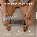 Gray Frida Mom Upside Down Peri Bottle being held by a person seated on a toilet, with text highlighting postpartum care benefits.