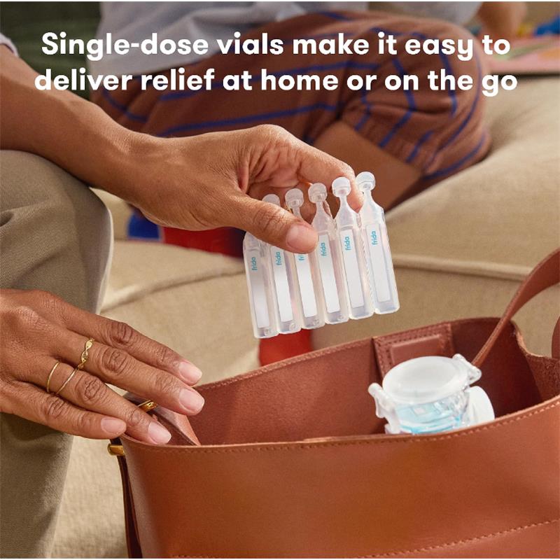 Sterile saline vials from Fridababy in a hand, being placed into a brown bag, with a nebulizer visible inside.