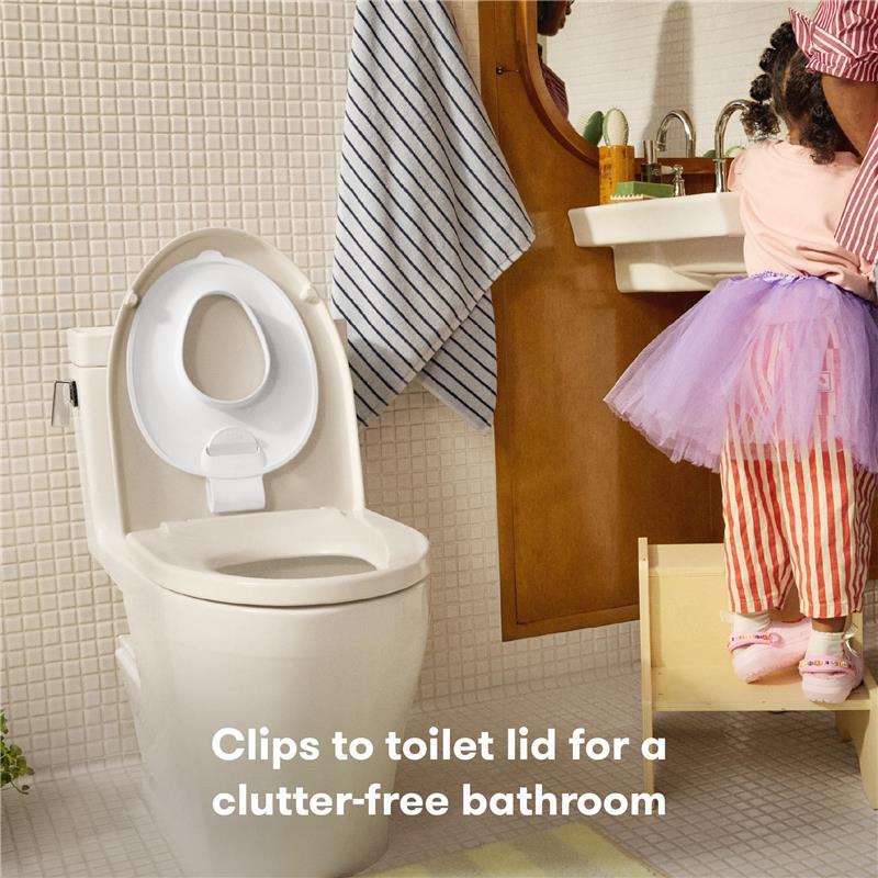 FridaBaby Drop Down Potty Training Seat, securely attached to a toilet lid, designed for easy toddler use and cleaning.