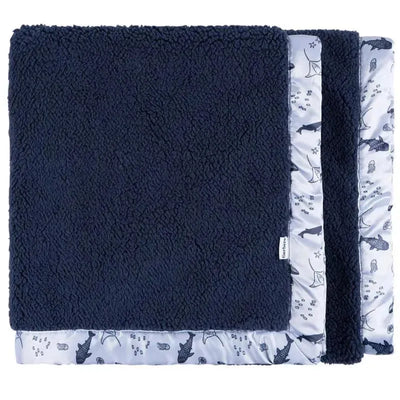 Plush navy blanket with a whale-themed patterned border, ideal for cozying up or nursery use.