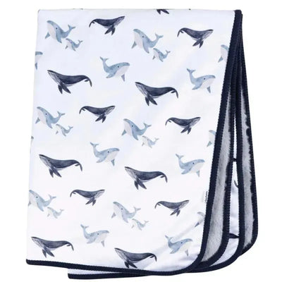 Plush blanket featuring whales in shades of blue and gray on a white background, ideal for cozying up.