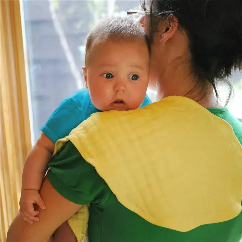 Organic muslin burp cloth draped over the shoulder of a caregiver holding a baby, both looking out a window.