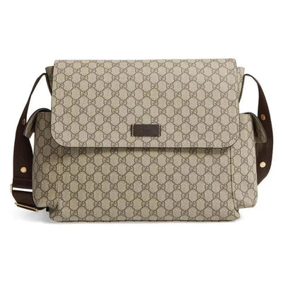 Gucci Supreme diaper bag in beige with signature logo pattern and brown shoulder strap, includes changing pad.