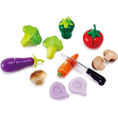 Colorful wooden toy vegetables including a tomato, broccoli, eggplant, and carrot, alongside a toy knife and cutting board.