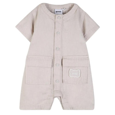 Ivory short sleeve linen romper for infants by Hugo Boss, featuring front buttons and two front pockets.