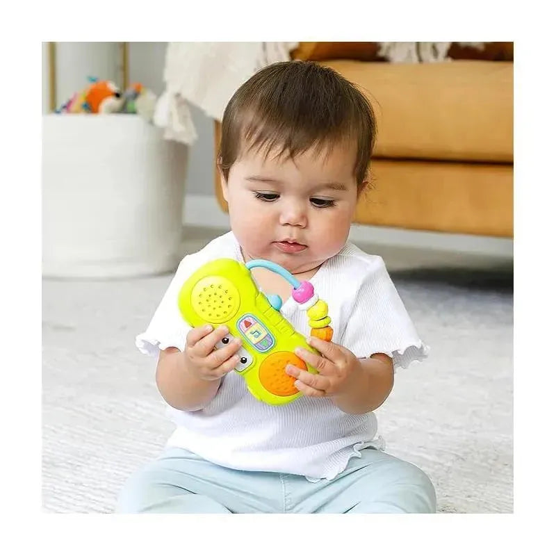 Infantino Wee Wild Ones Music & Light Mini Boombox held by a toddler, featuring colorful buttons and lights, in a cozy room.