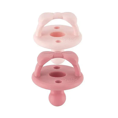 Orthodontic silicone pacifiers in ballet slipper and primrose colors, designed for babies 0-6 months.