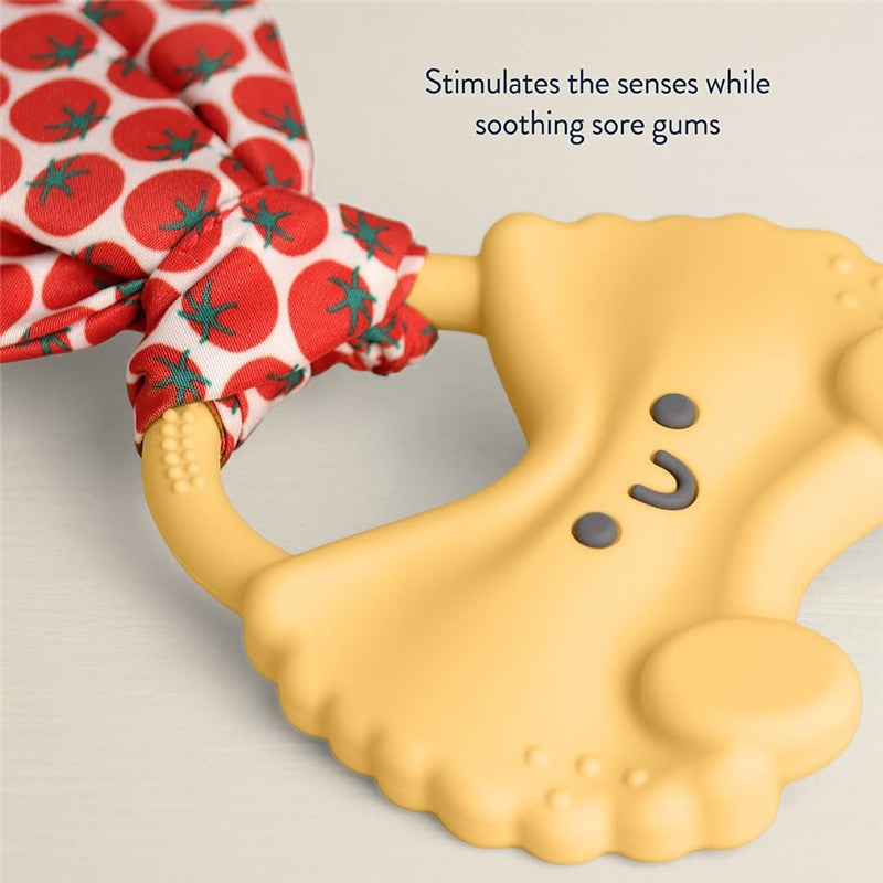 Pasta-shaped silicone teether with a crinkle tie, featuring a happy face and tomato-patterned fabric, soothes sore gums.