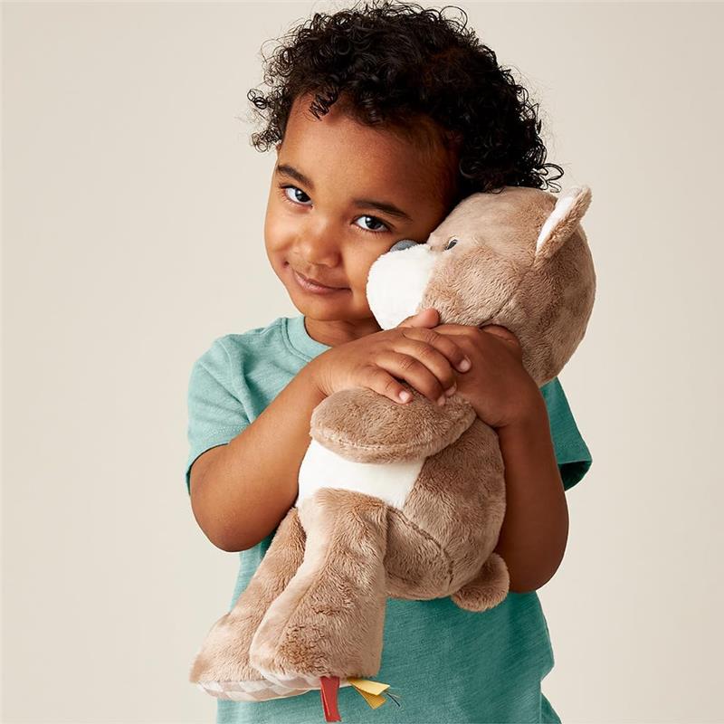 Child cuddles an Itzy Ritzy Snuggles Plush Toy bear, showcasing its soft texture and playful design.