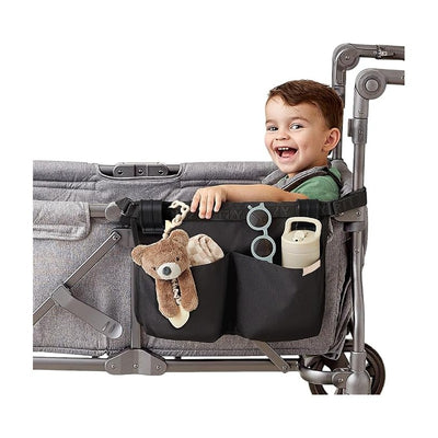 Travel organizer with three pockets and four toy loops in black, attached to a stroller, storing a teddy bear, blanket, and sippy cup.