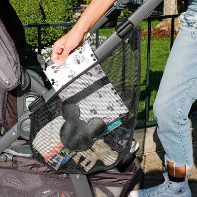 Side Sling Stroller Cargo Net by J.L. Childress, featuring a mesh design and Mickey Mouse graphics, holds various items.