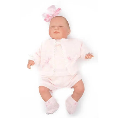 Realistic JC Toys Baby Doll in a pink outfit with a matching headband and booties, eyes closed, lying on a white background.