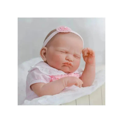 JC Toys Berenguer Classics Leonor reborn baby doll wearing a pink outfit and headband, with a relaxed expression.