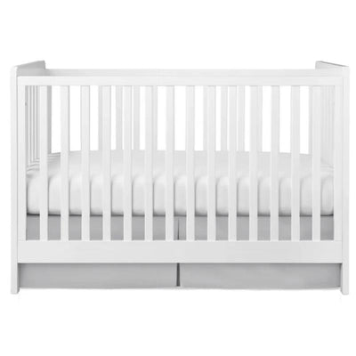 Gray pleated crib skirt underneath a white crib, featuring a fitted mattress with visible seams.