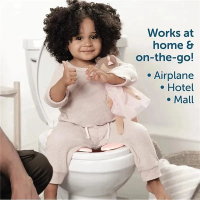Toddler sitting on a toilet with a folding travel potty seat, giving a thumbs-up while holding a doll.