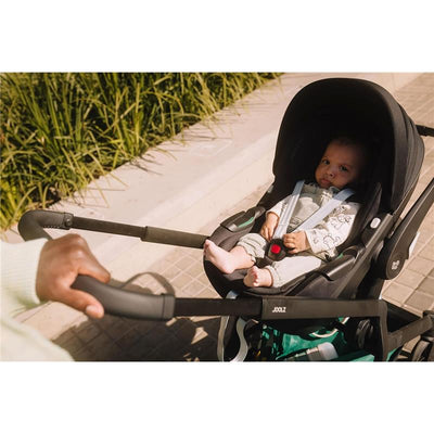 Joolz Hub2 stroller with a seated baby, held by an adult pushing the stroller.