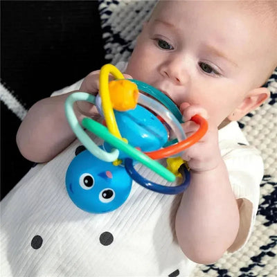 Colorful Kids II Opus’s Shake & Soothe teether toy and rattle held by a baby, featuring a blue animal face and multiple rings.