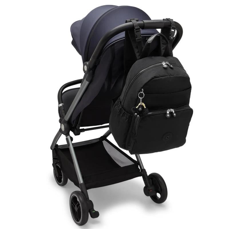 Kipling Maisie Diaper Backpack in Tiny Black Noir attached to a stroller, featuring two zippered pockets and a keychain charm.
