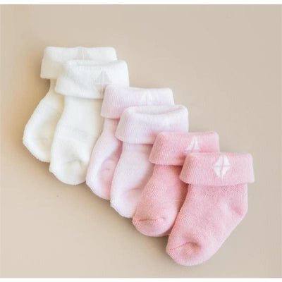 Three pairs of soft, pastel-colored baby socks in white, light pink, and darker pink, featuring a rolled cuff design.