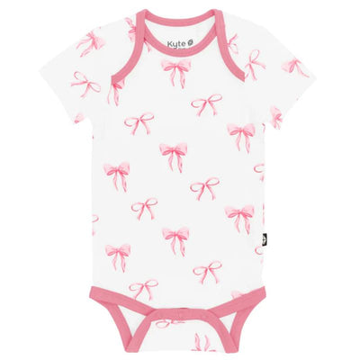 Kyte Baby bodysuit featuring a white background adorned with pink bow patterns and pink trim around the neckline and legs.