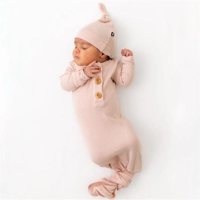 Ribbed blush knotted gown with two wooden buttons and matching hat on a sleeping baby.