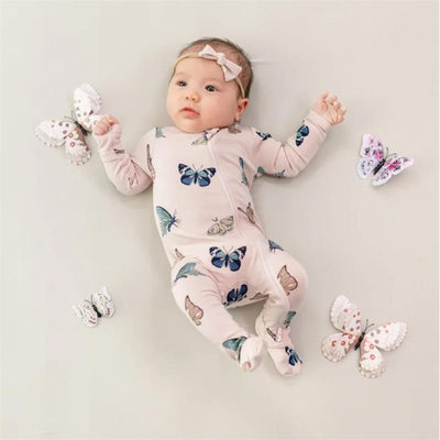 Zippered footie for infants in blush with colorful butterfly patterns, featuring a baby girl lying on a light background surrounded by butterfly toys.