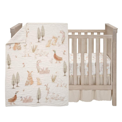 3-pack bunny hop organic cotton bedding set featuring whimsical animal illustrations, displayed on a crib.