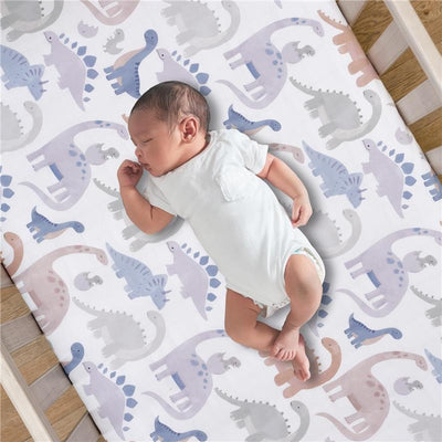 Fitted crib sheet featuring colorful dinosaur patterns with a sleeping baby in a white onesie.