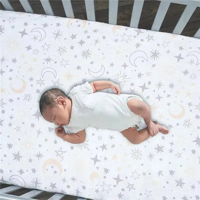 Fitted crib sheet featuring a moon and stars design with a sleeping baby on it, promoting a calming bedtime atmosphere.