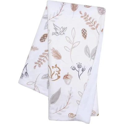 Woodland-themed blanket featuring a soft white fabric with illustrations of a fox, leaves, and pinecones in neutral colors.
