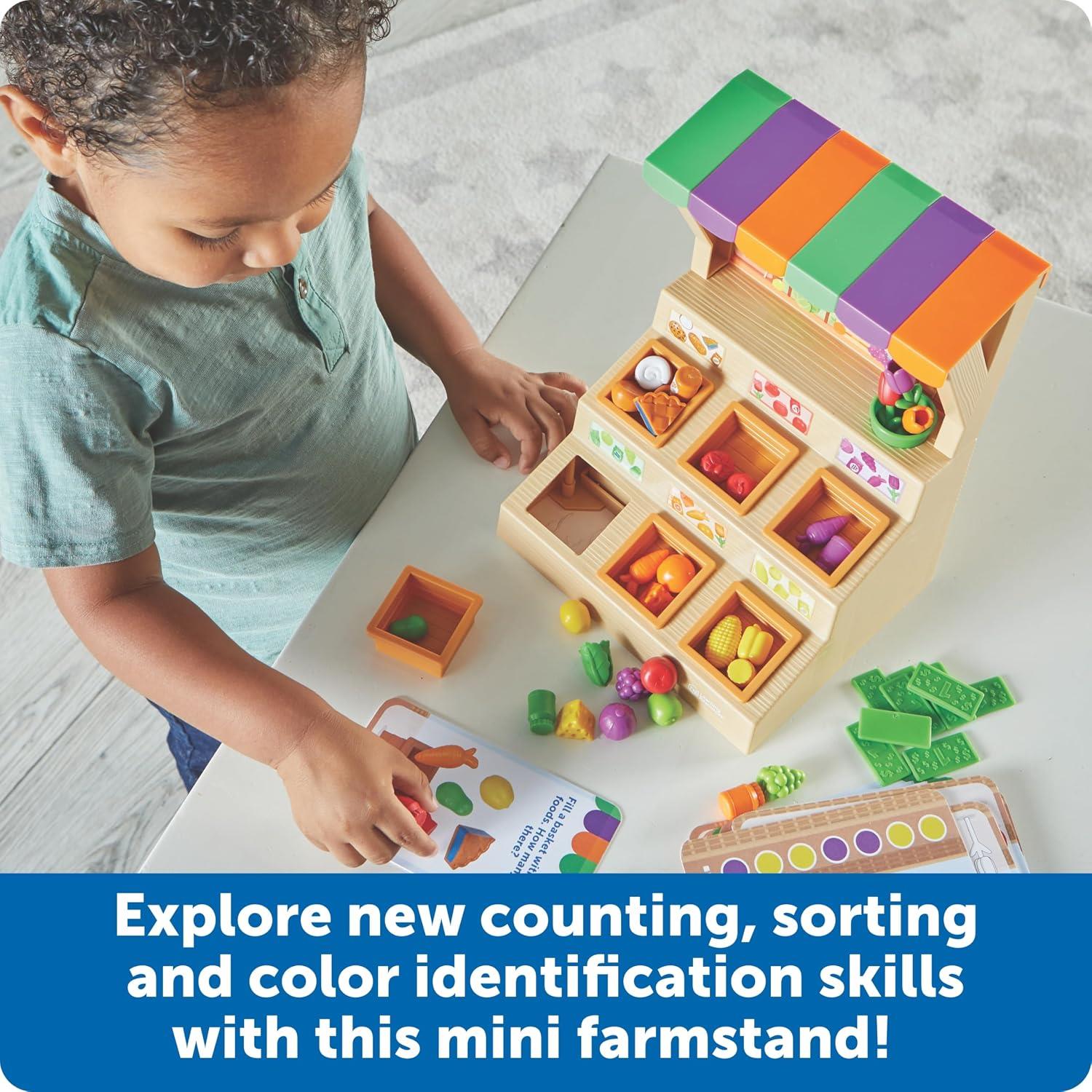 A child engages with the Learning Resources Mini Farmstand Sorting Set, sorting colorful fruits and vegetables into bins while utilizing a sorting guide.