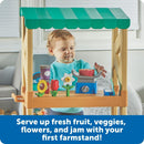 Child playing with the Learning Resources My First Farmstand, featuring fruits, veggies, and flowers on a wooden stand.
