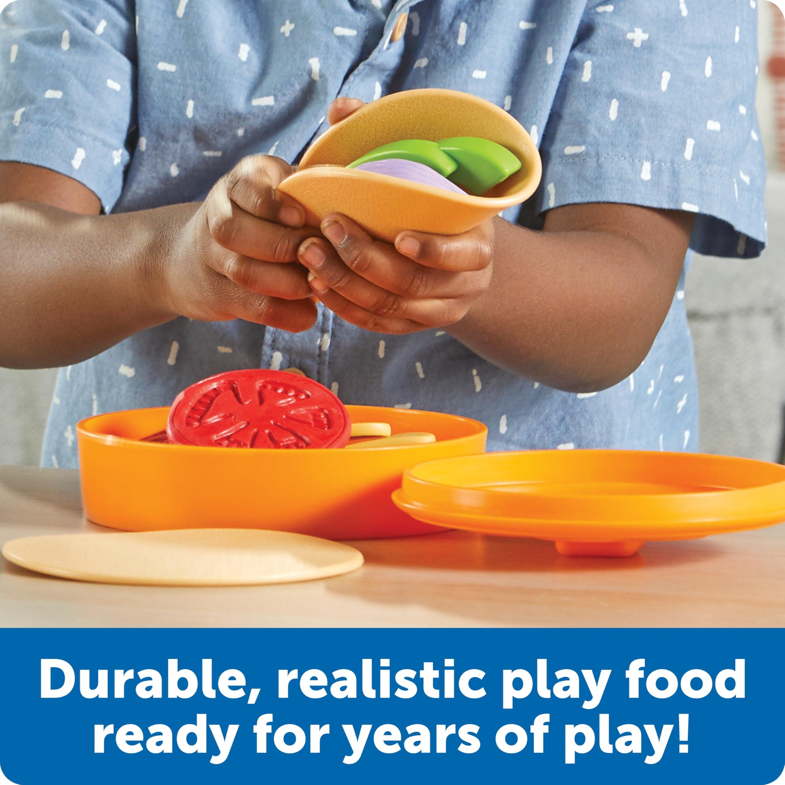 Child assembling a taco with colorful play food items, including tortillas, lettuce, and tomato, in an orange container.
