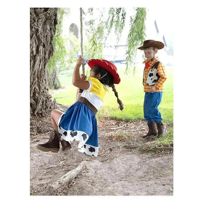 Children dressed in cowboy costumes, one swinging on a rope swing and the other watching, showcasing playful outdoor fun.