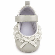 Ankle strap shoe in white with lace trim and bow detail, designed for infants.