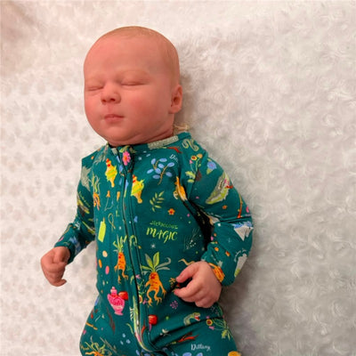 Reborn doll named Kimberly made of white vinyl, featuring painted hair and closed eyes, wearing a colorful patterned onesie.