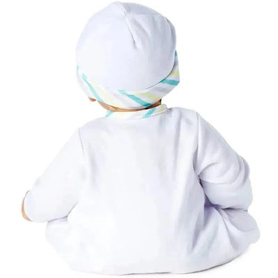 Light-skinned doll with brown eyes and black hair, wearing a white outfit and a striped hat, seated and facing away.