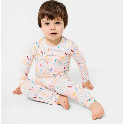 Long sleeve pajama set for toddlers featuring colorful doodle patterns, worn by a young child sitting on the floor.